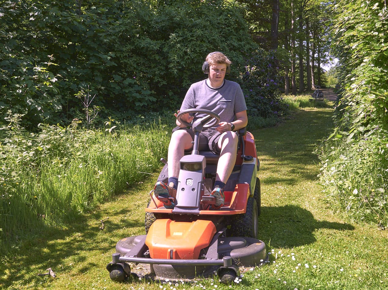 Hovenier maait een natuurlijke grasweide op een zitmaaier
